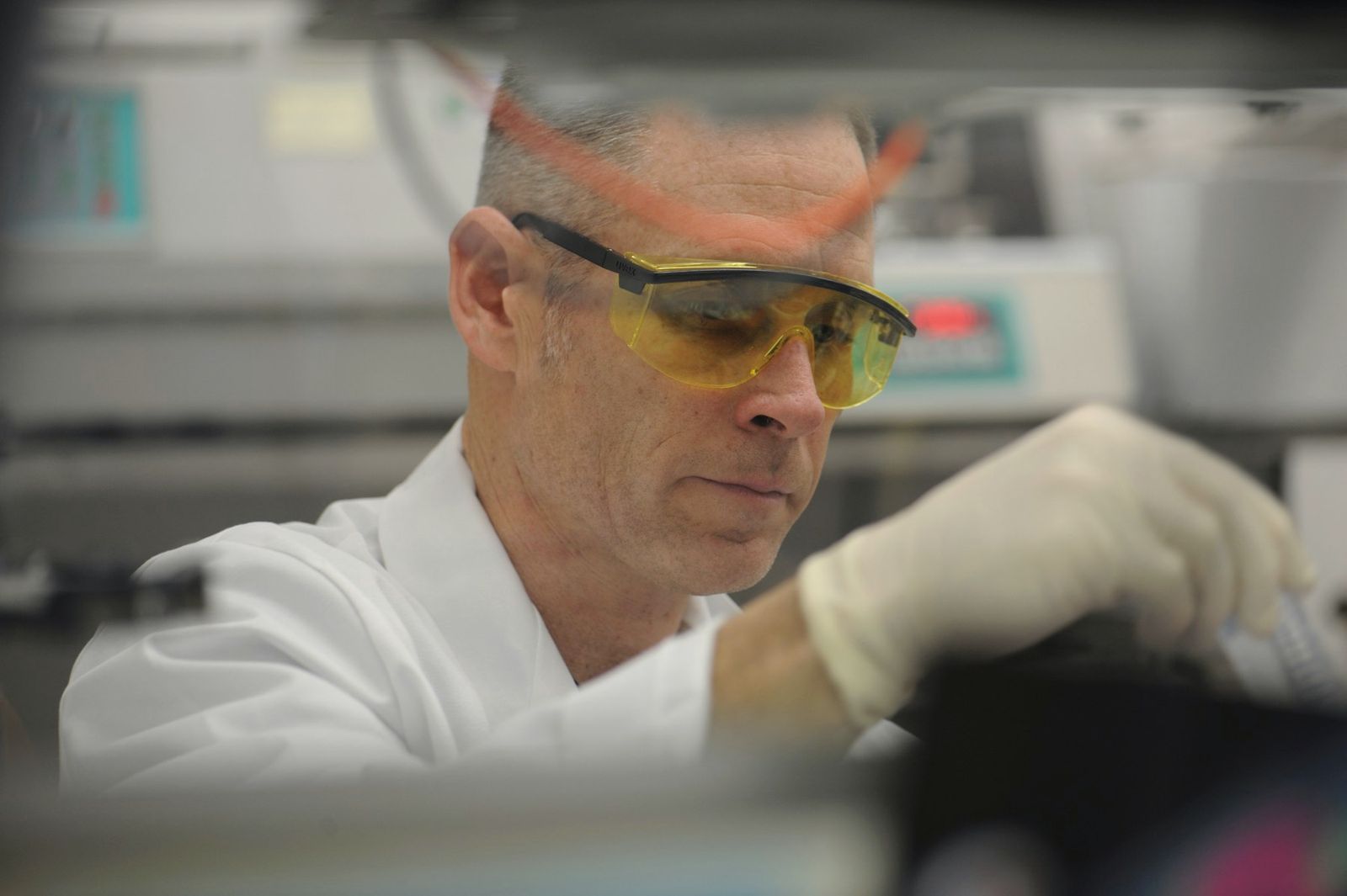 Male scientist in safety glasses and gloves working with lab equipment