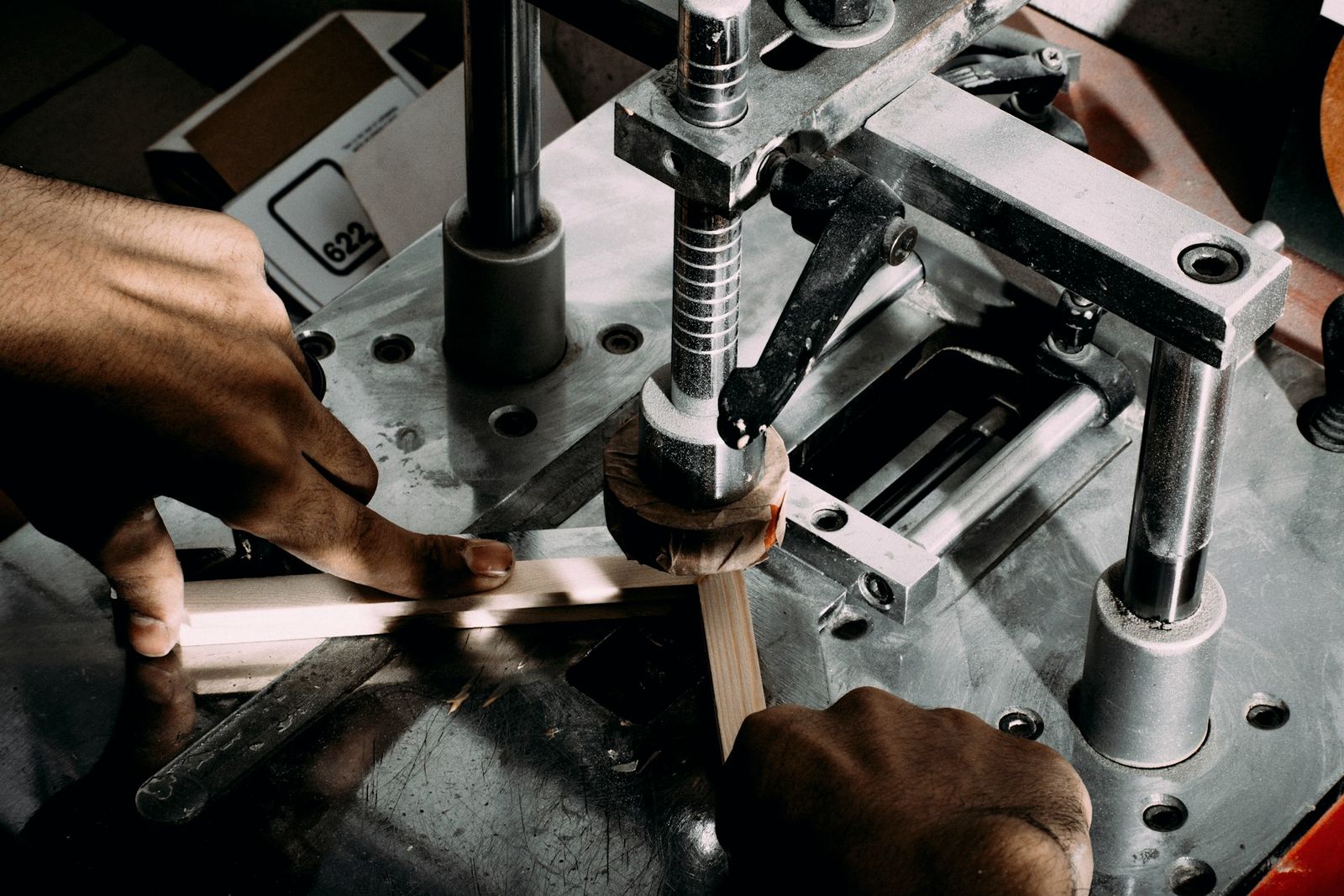 Hands guiding a part through precision metalworking machinery