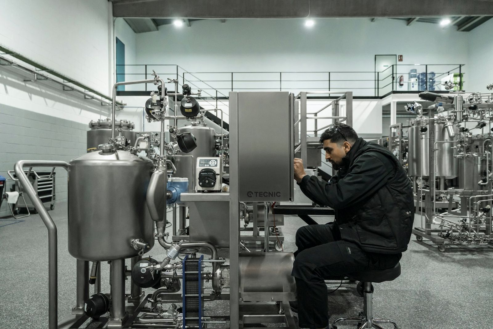 Engineer working on stainless steel processing equipment in a clean manufacturing hall
