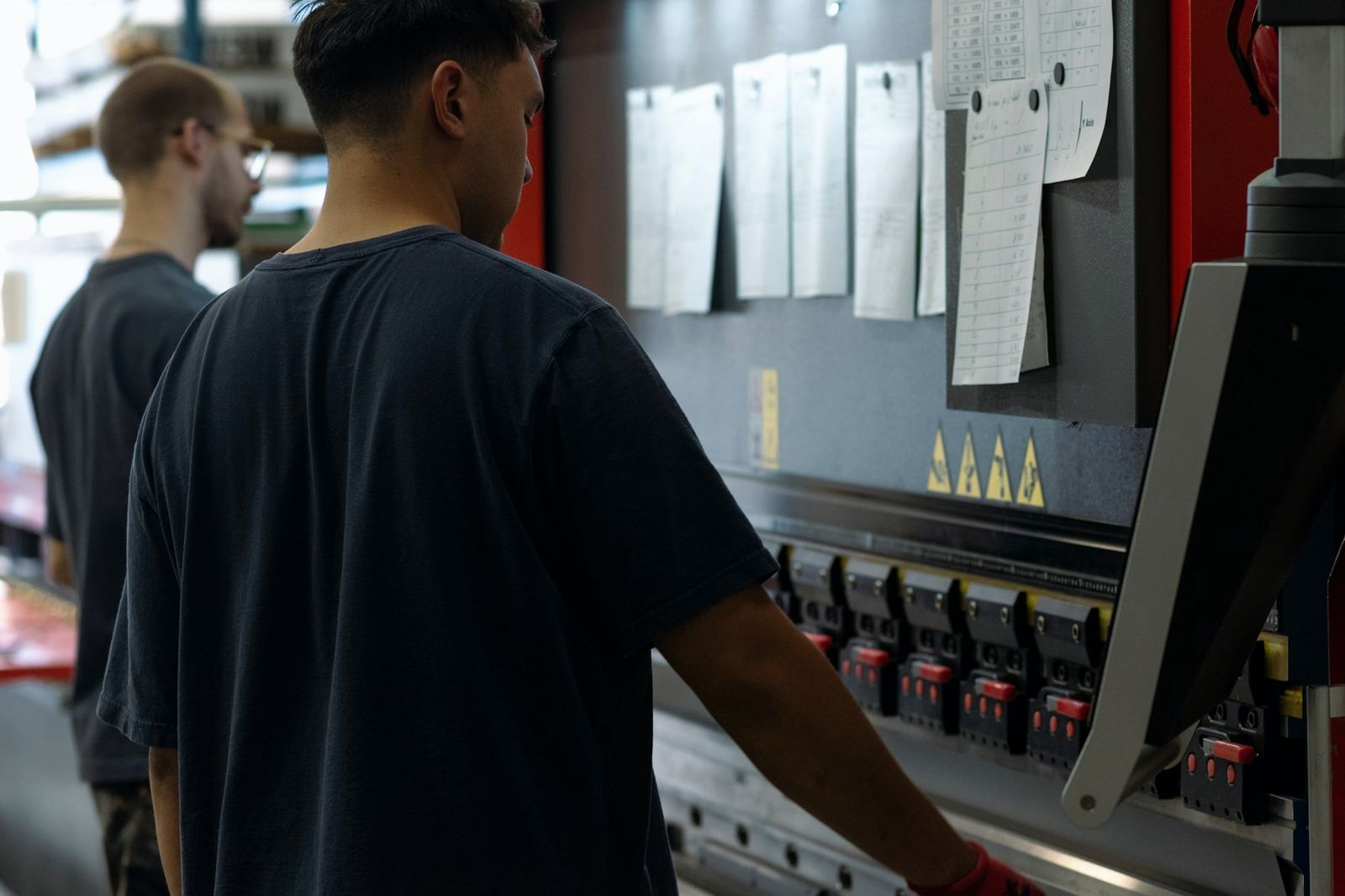 Two workers standing at an industrial press in a factory