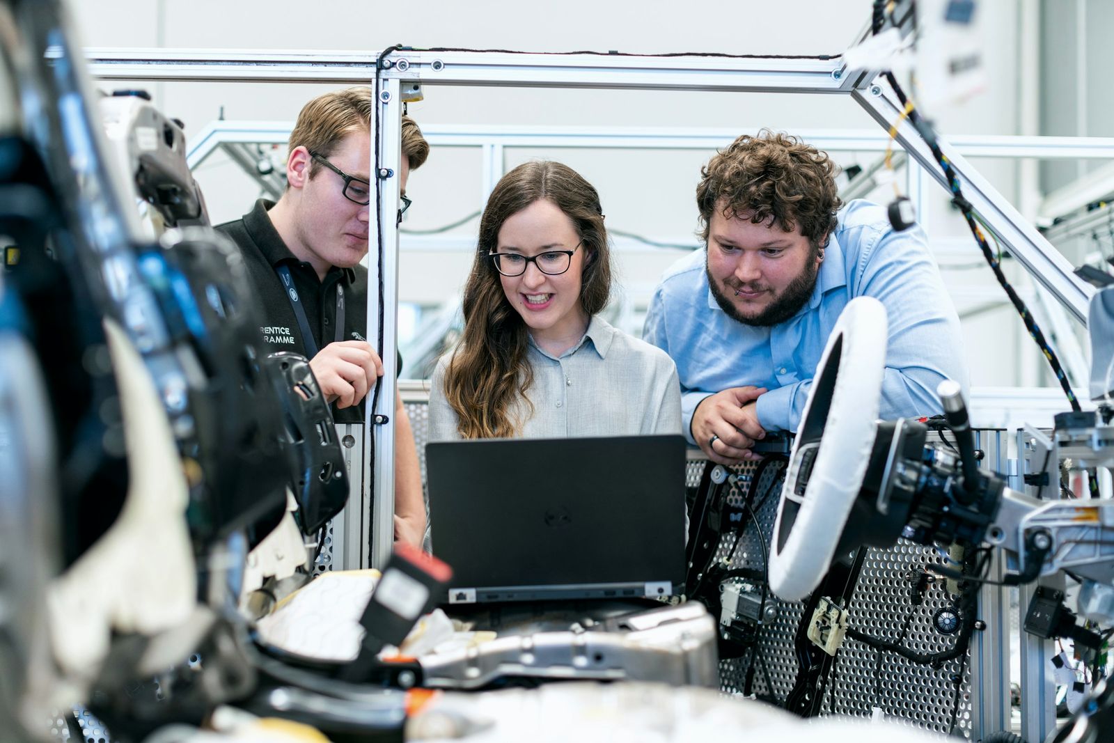 Three engineers reviewing test data on a laptop beside automated equipment